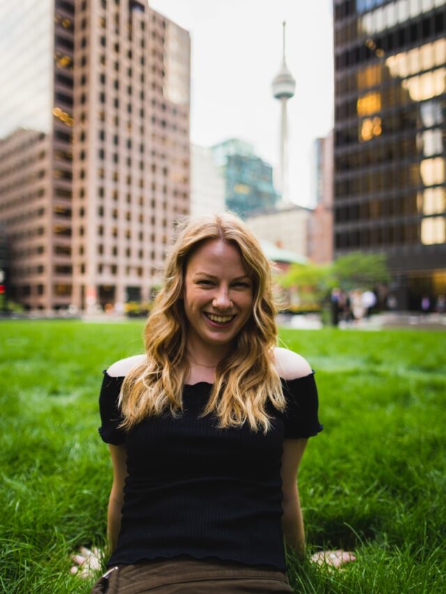 a woman sitting in the grass in a city park